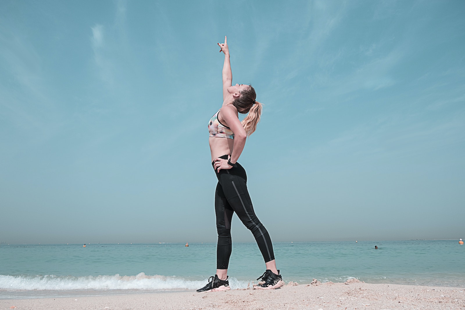 Woman Pointing at Sky on Seashore